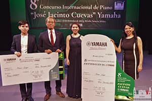 Los ganadores de ambos grupos Matheus Enzo (Brasil) de Grupo "Jóvenes" y Bárbara Prado (México) de Grupo "Mayores" recibiendo sus premios Yamaha por parte del Sr. Kentaro Takei